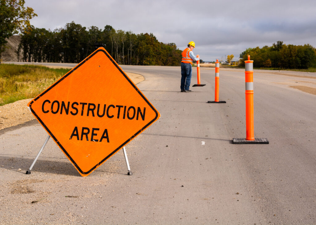 Laborer setting up safety cones in a construction zone. Taking Precautions Around California Construction Zones