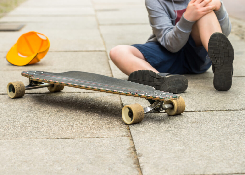 Skateboarder on the ground suffering from a knee injury.