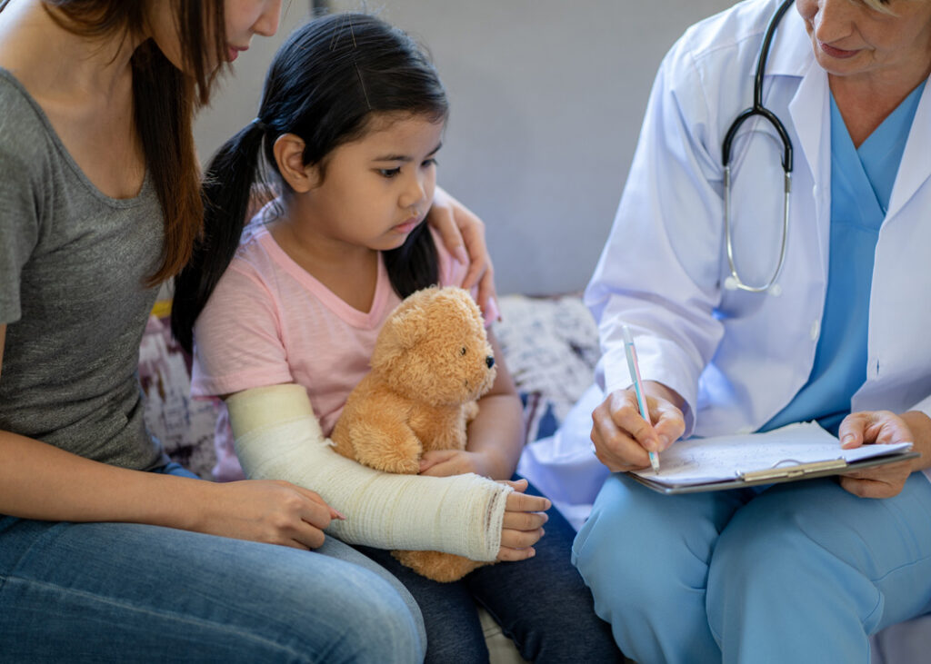 doctor examining little girl with a broken arm