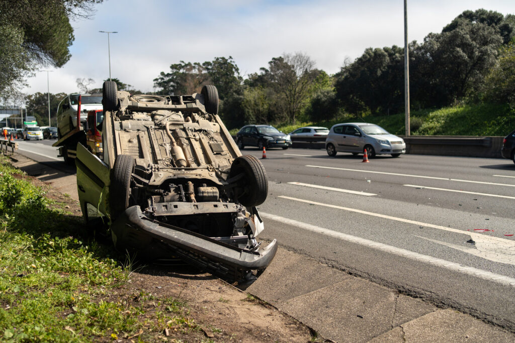 Destroyed car after accident lying upside down on roadside during day