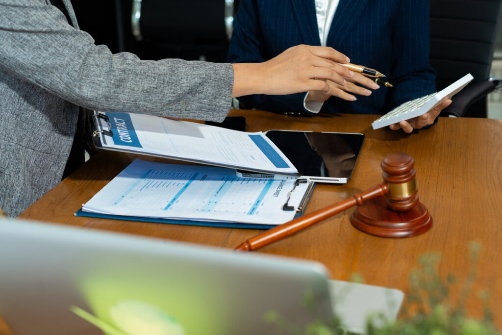 Lawyer team or accounting department writes a note and uses a calculator to calculate expenses - income. at office lawyer.