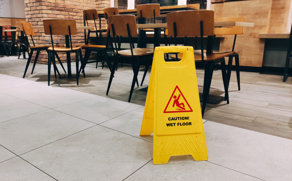 Banner on floor of yellow colour with caution wet floor inside the restaurant