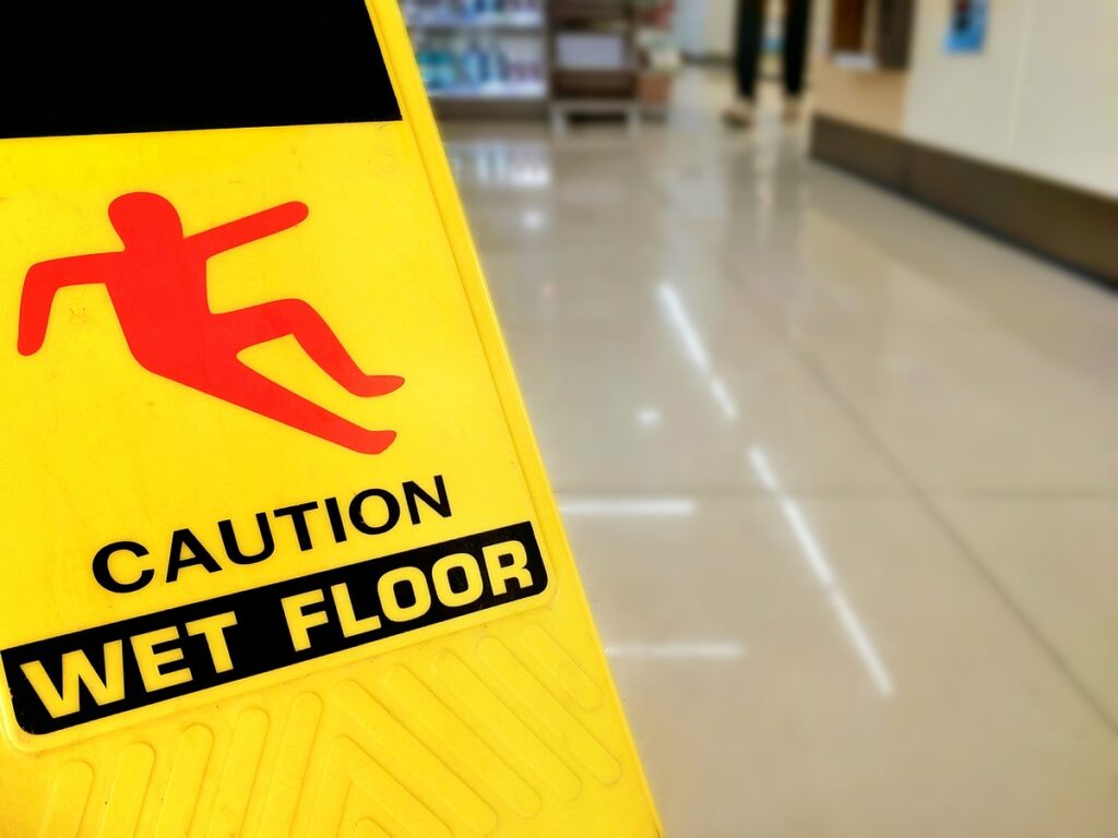 Focus on warning sign beware slippery floor and blur background of aisle inside the supermarket on sign and symbol with safety concept