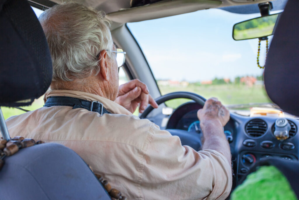 an elderly man is driving a car