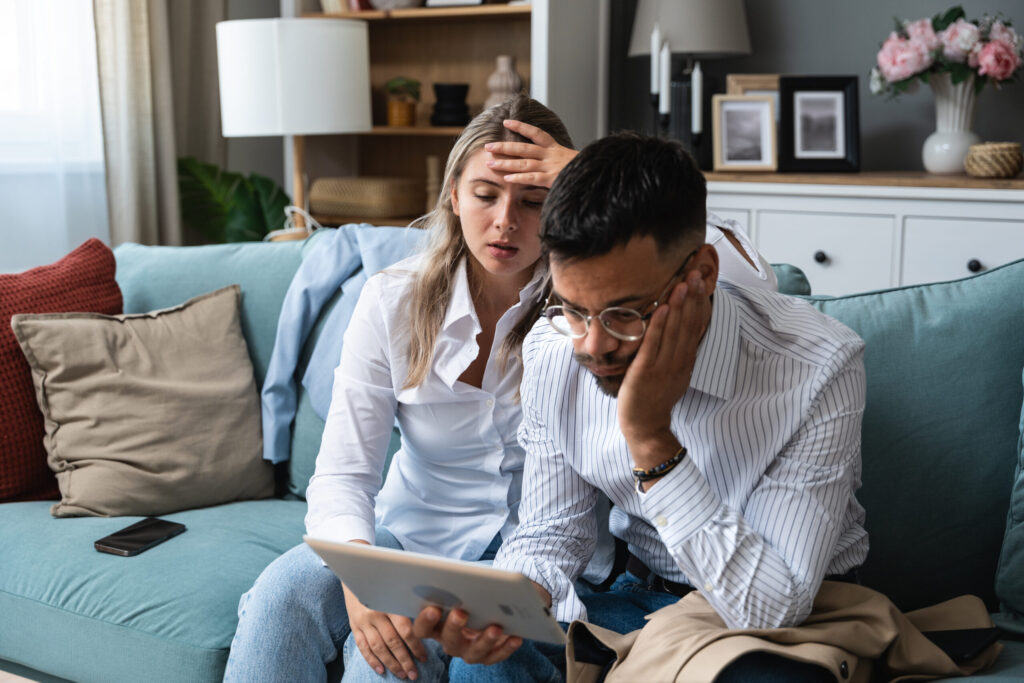 Sad nervous businessman and businesswoman small company owners looking on digital tablet screen negative news. Not what they planned, bad informations and email from employees