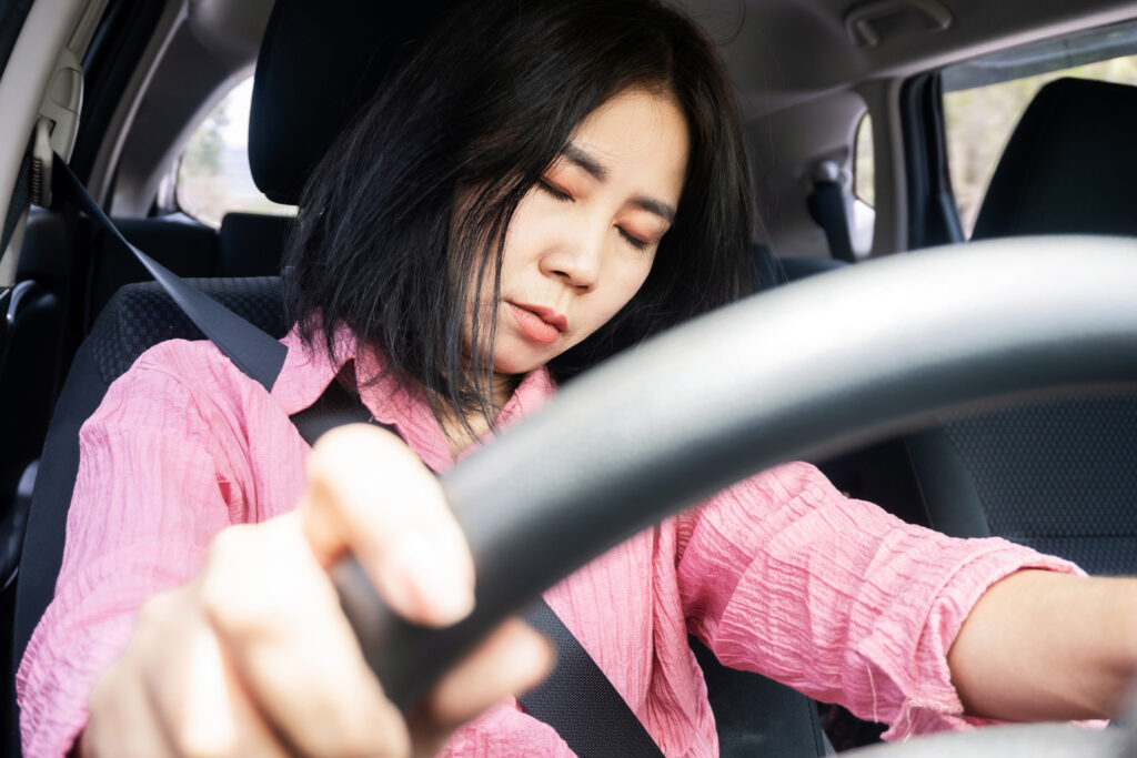 Sleepy and Fatigued Asian Woman Falls Asleep while Driving, the Danger of Drowsy Driving, unsafe driving behavior concept